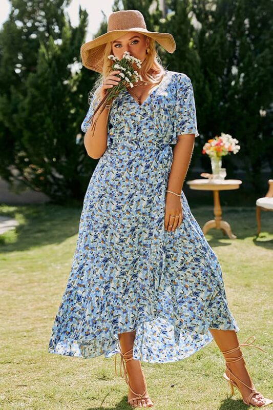 Femme en robe bohème grande taille bleue à imprimé léger, coiffée d’un chapeau de paille