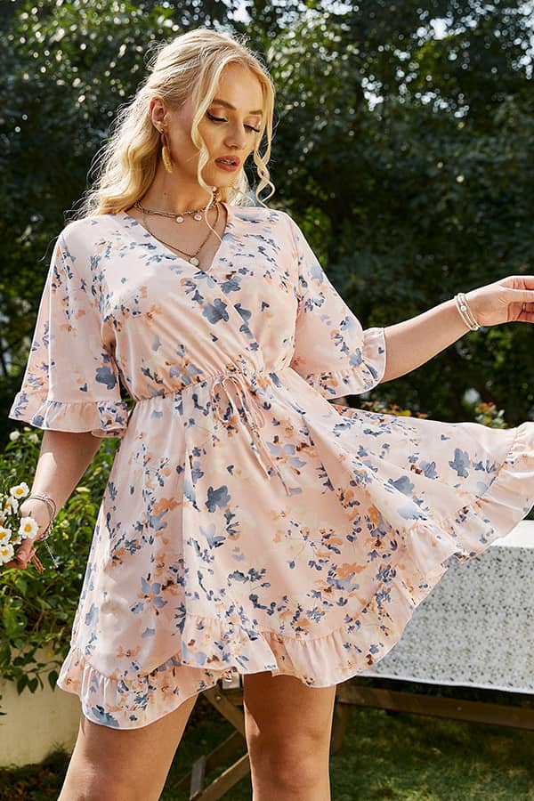 Femme portant une robe champêtre grande taille rose pâle à fleurs, coupe fluide et romantique